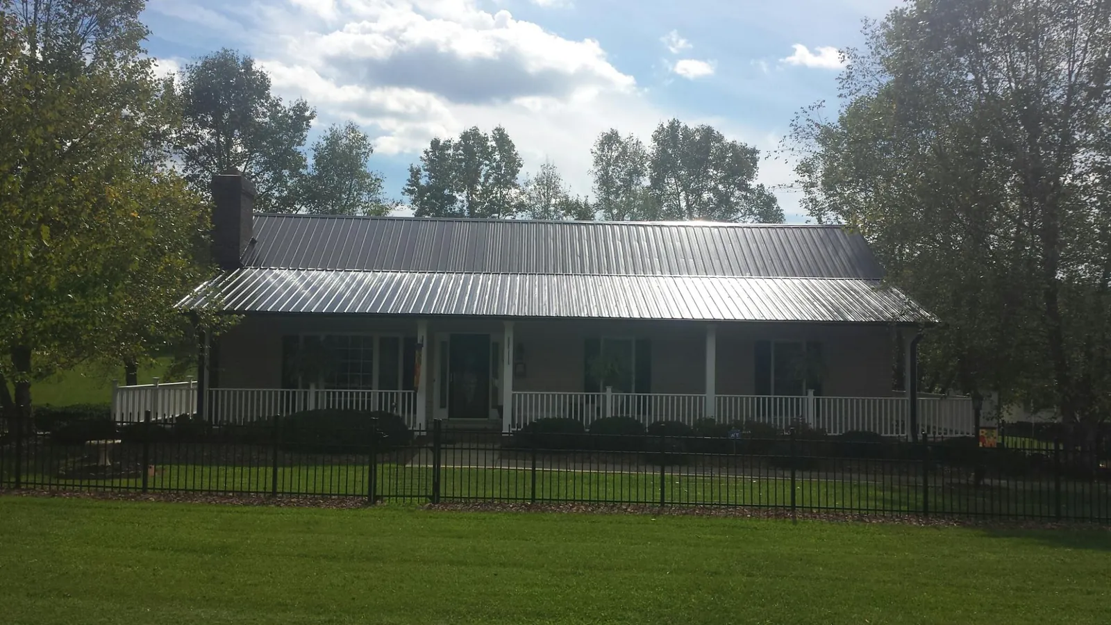Gray metal roof on a brick ranch with a full width front porch — Gutter Guard Installation work by our crew in Cynthiana