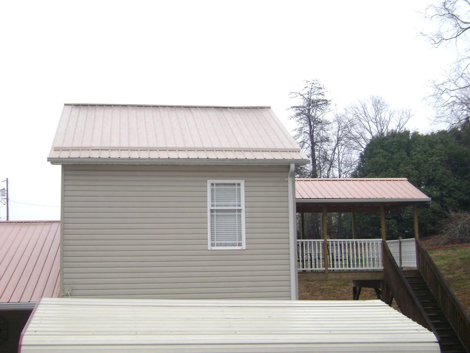 Tan metal roofs on a two story addition and attached porch, from a Roof Replacement job in Cynthiana